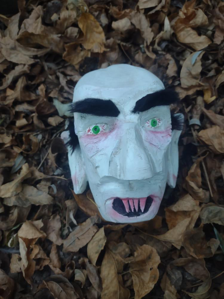 Hand-carved Dracula mask by 1 Awesome Turner, staged in autumn leaves